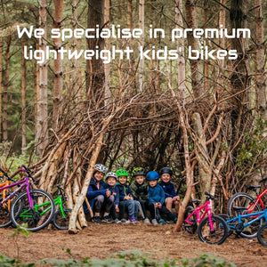   A group of kids take shelter in the forest inside their newly-built den with their bikes propped up outside. 